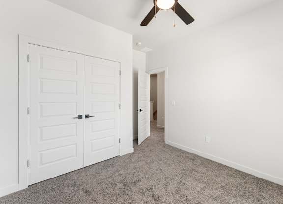 A room with a ceiling fan and two white doors.