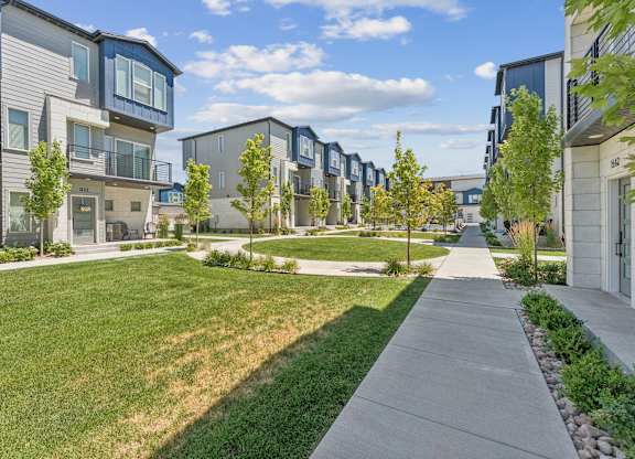 A row of modern townhouses with green lawns in front.