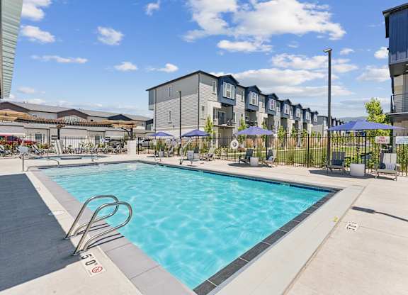 A swimming pool surrounded by a fence and apartment buildings.