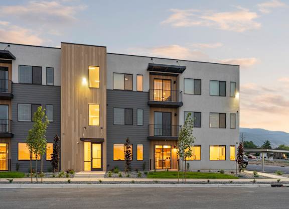 A modern apartment building with balconies and trees in front.