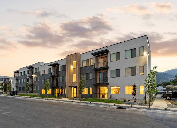 A modern apartment building with a parking lot in front.