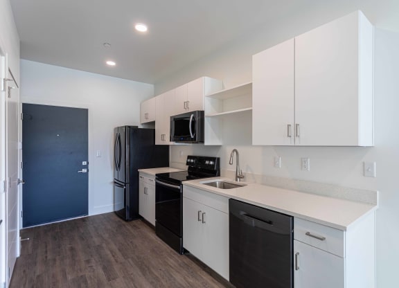 a kitchen with white cabinets and black appliances and a black refrigerator