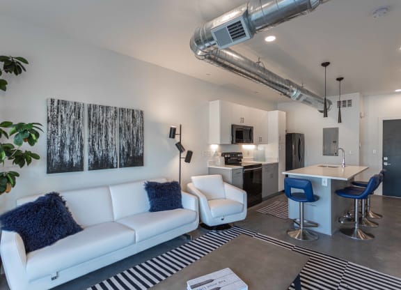 an open living room and kitchen with a couch and chairs