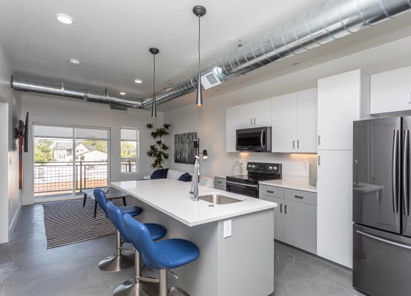 a kitchen with an island with blue chairs and a stainless steel refrigerator