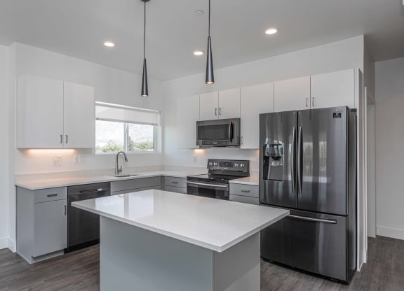 a white kitchen with stainless steel appliances and white counter tops