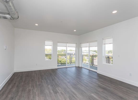 a living room with white walls and wood floors and a balcony