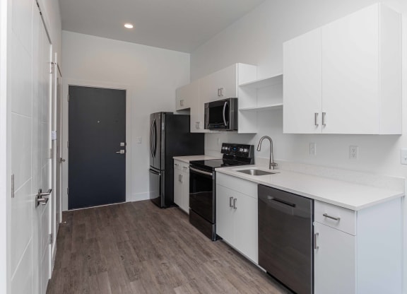 a kitchen with white cabinets and a black refrigerator
