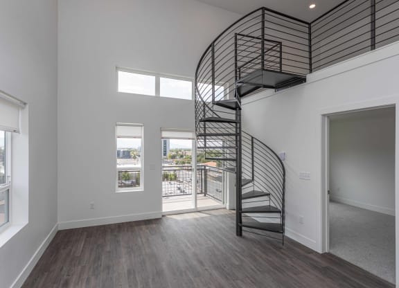 a spiral staircase in a living room with white walls and wood floors