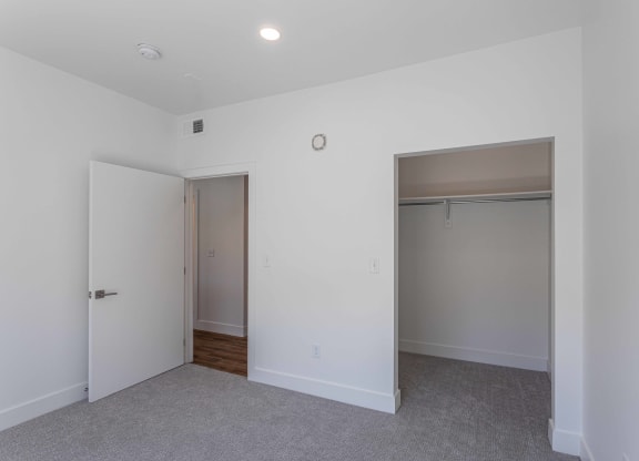 an empty bedroom with a closet and a door to a bathroom