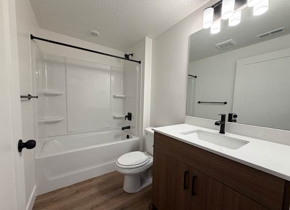 A white bathroom with a toilet, sink, and shower.