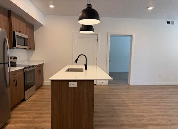 A kitchen with a white countertop and wooden cabinets.