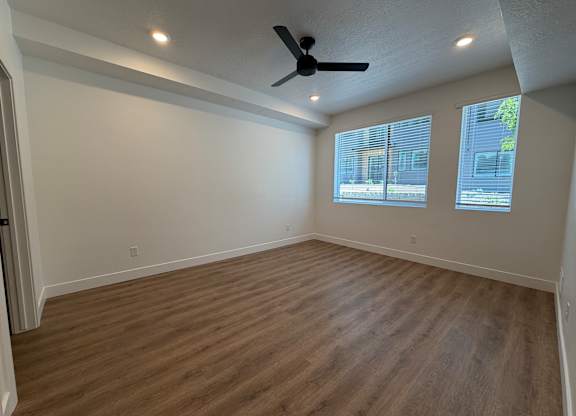 A room with a ceiling fan and wooden flooring.