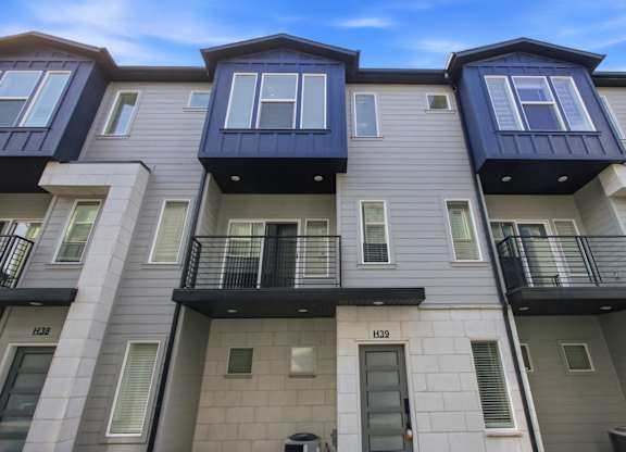 The image shows a modern apartment building with balconies and doors.