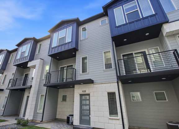 A row of modern townhouses with balconies and doors.