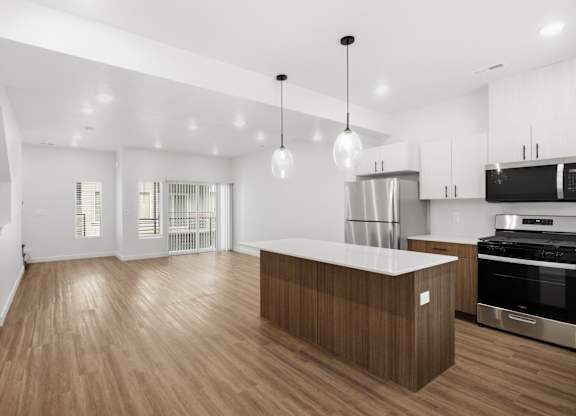 A modern kitchen with wooden floors and stainless steel appliances.