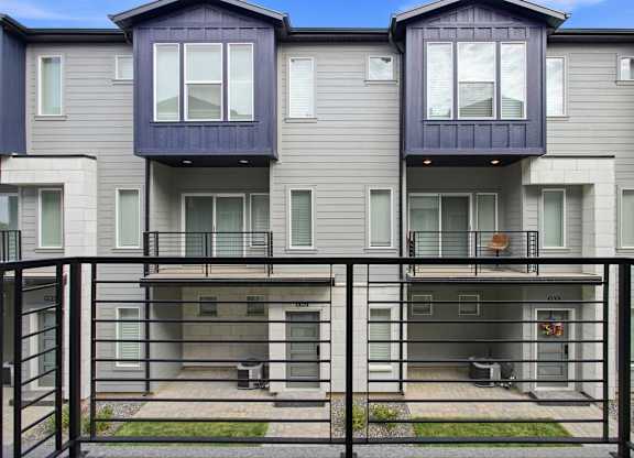 A row of townhouses with a black fence in front.
