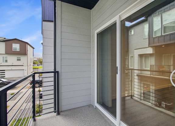 A balcony with a glass door leading to a room.