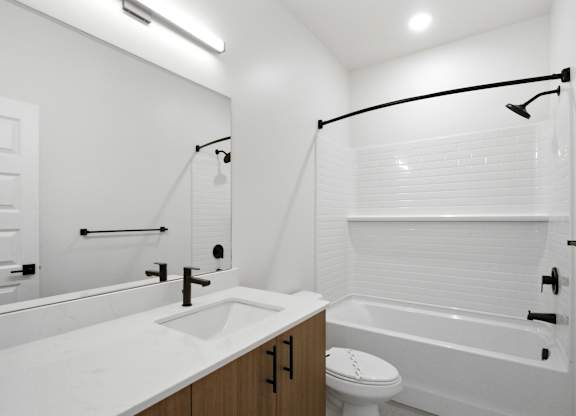 A white bathroom with a toilet, sink, and bathtub.