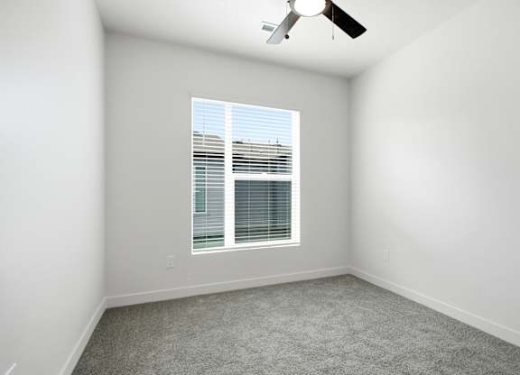 A room with a ceiling fan and a window with blinds.