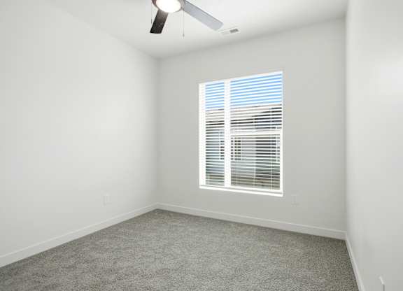 A room with a carpeted floor and a window with blinds.