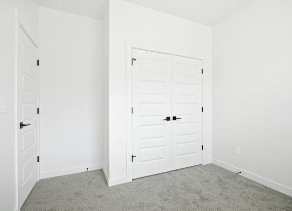 A white door with a black handle is in a room with white walls.