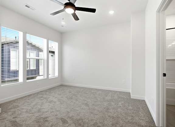 A room with a ceiling fan and carpeted floor.
