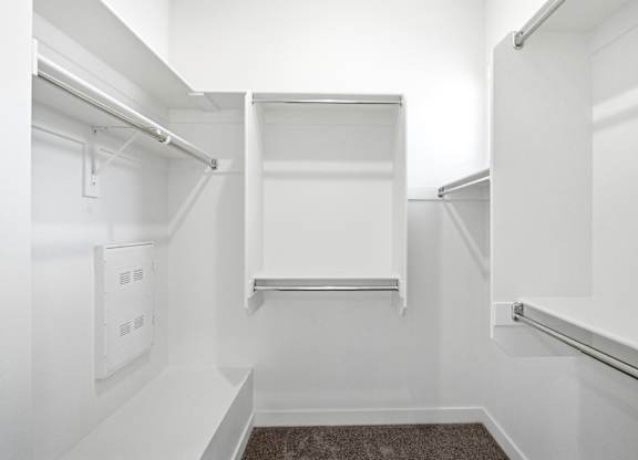A white walk-in closet with shelves and a carpeted floor.