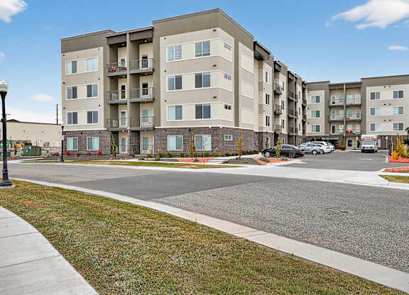A large apartment complex with a parking lot in front.