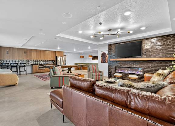 A living room with a brown leather couch and a fireplace.