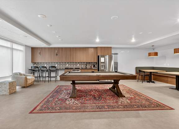 A living room with a rug on the floor and a dining table in the middle.