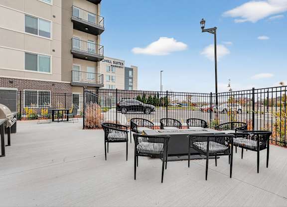 A patio area with a table and chairs is surrounded by a black fence.