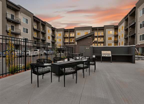 A patio with chairs and a table is surrounded by apartment buildings.