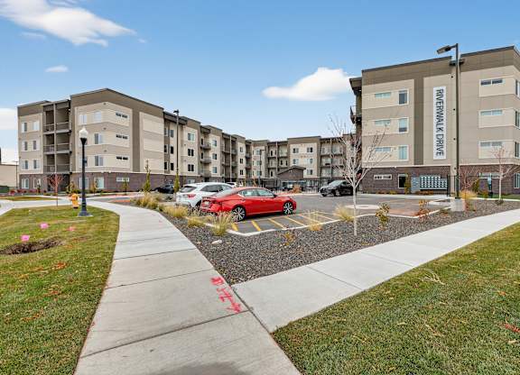 A red car is parked in a parking lot in front of a building with the name "REVERWALL CAVE" on it.