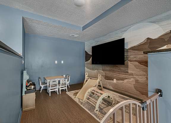 A room with a dining table and chairs, a television, and a staircase with a railing.