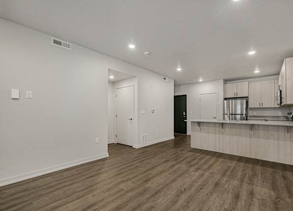 A kitchen with white cabinets and a wooden floor.