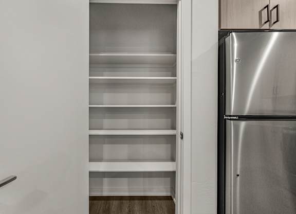 A kitchen with a refrigerator and empty shelves.