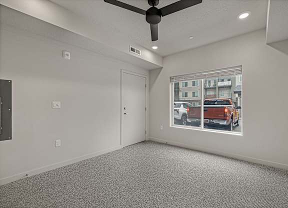 A room with a ceiling fan and a window showing a street view.
