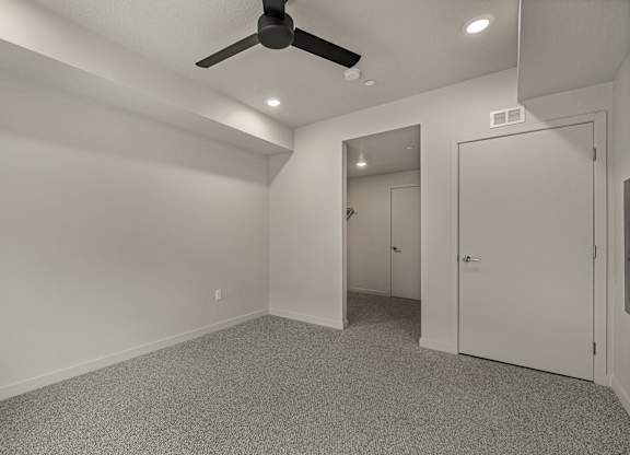 A room with a ceiling fan and carpeted floor.
