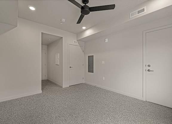 A room with a ceiling fan and carpeted floor.