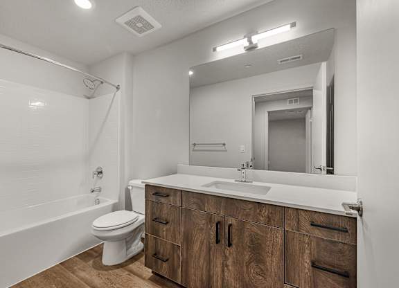 A modern bathroom with a wooden vanity and white fixtures.