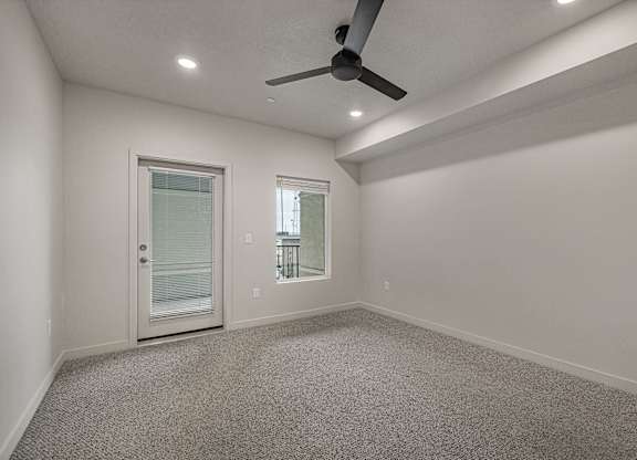 A room with a ceiling fan and two windows.