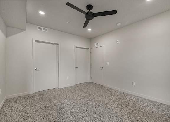 A room with a ceiling fan and three doors.