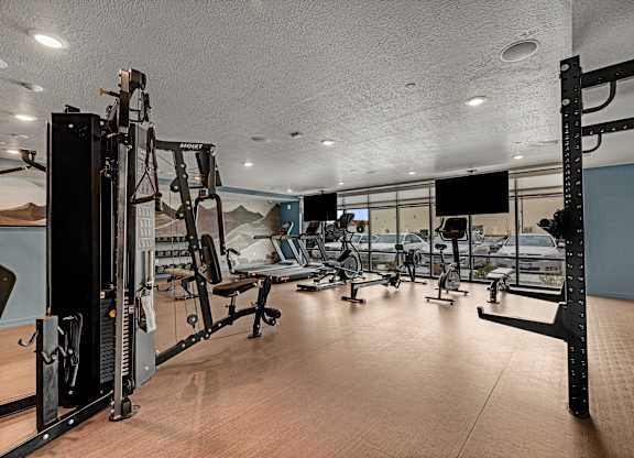 A gym with a variety of equipment including a squat rack, bench press, and a mirror.