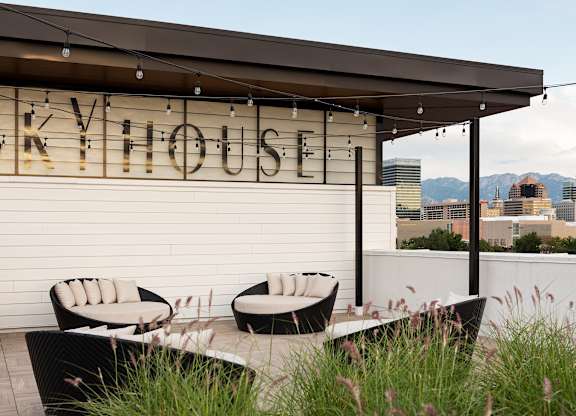 A patio area with a table and chairs in front of a building with the name "SKYHOUSE" on it.