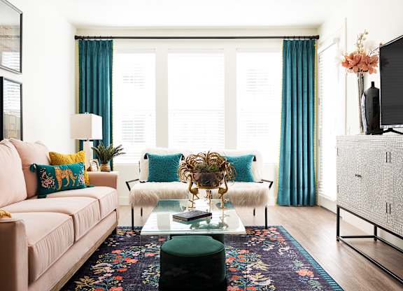 A living room with a pink couch, a coffee table, and a television.