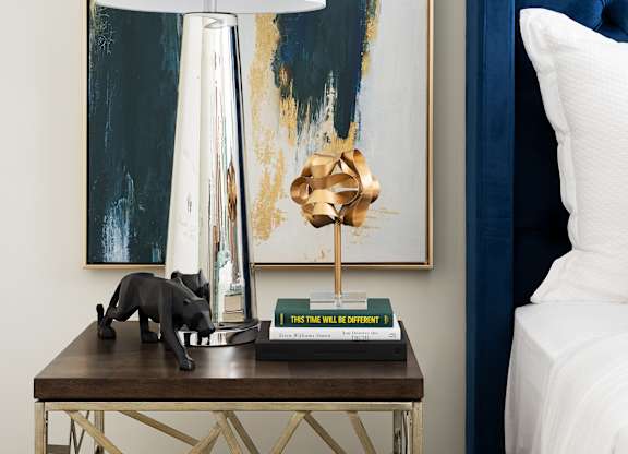 A table with a lamp and a painting on the wall.