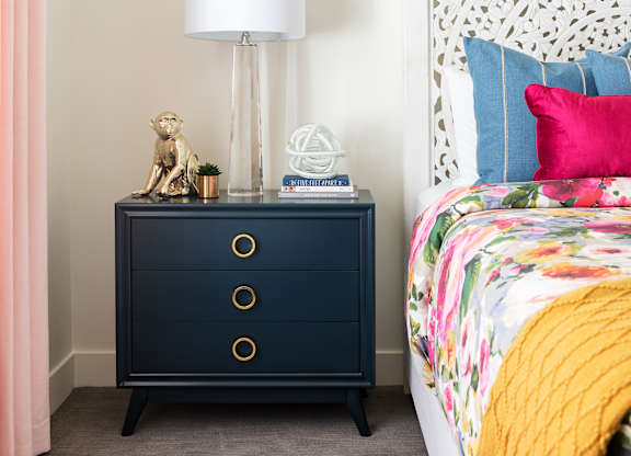 A bedroom with a bed, a nightstand with a lamp, and a curtain.
