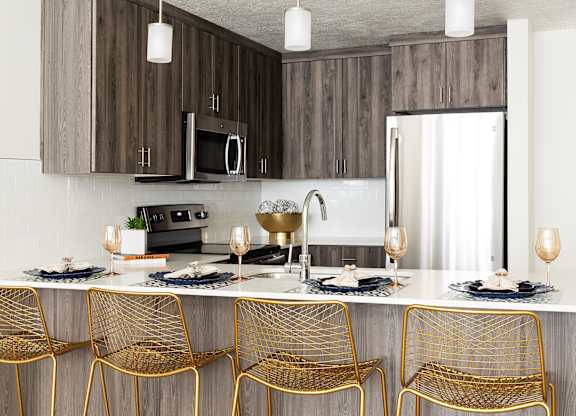 A modern kitchen with a bar area and chairs.