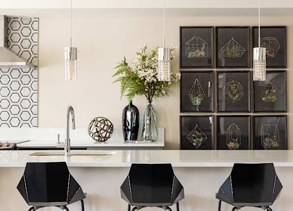 A kitchen with a white counter top and black bar stools.