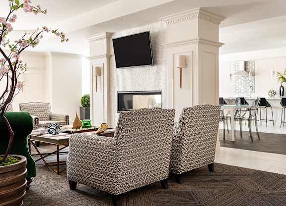 A living room with a fireplace and a television mounted above it.